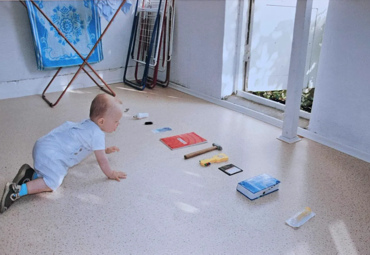 Baby crawling toward a row of objects laid out on the floor