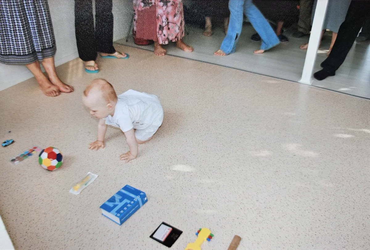 Baby sitting next to the floppy disc while family watches from the side